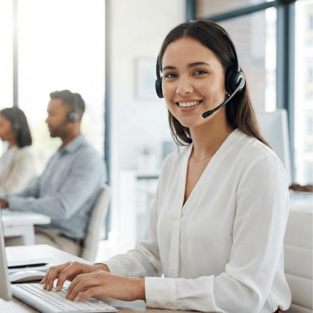 Secrétaire d’accueil portant un casque téléphonique, travaillant sur ordinateur dans un bureau lumineux, représentant le service secrétariat de SoluFrance.