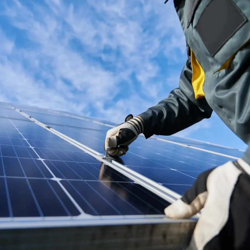 Technicien Solufrance installant des panneaux solaires sur une toiture, vue en gros plan.